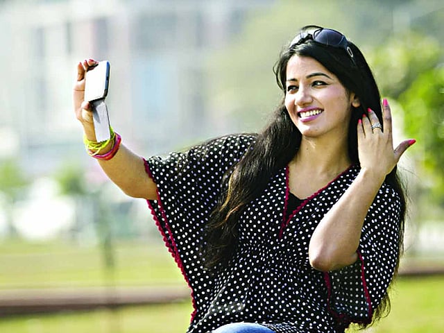 হাতে আছে স্মার্টফোন। নিজের ছবি তুলে নিজেই করি আপলোড । মডেল: শিল্পী, ছবি: অধুনা