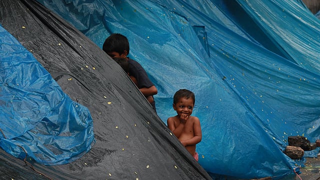 বৃষ্টির দুর্ভোগ সয়ে ফুটপাতে আশ্রয় নেওয়া ছিন্নমূল মানুষের শিশু। ছবিটি আজ বেলা সাড়ে ১১টার দিকে রাজধানীর পলাশী মোড়-সংলগ্ন এলাকা থেকে তোলা। ছবি: জাহিদুল করিম