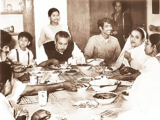 শেখ রাসেল, বঙ্গবন্ধু, তঁার পেছনে শেখ রেহানা, শেখ জামাল, বেগম ফজিলাতুন্নেছা মুজিব ও অন্যান্য। তঁারা কখনো একা খেতেন না