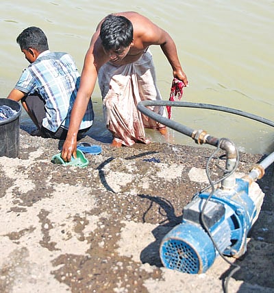 সুরমা নদীর সিঁড়িতে উন্মুক্তভাবে মোটর বসিয়ে পানি উত্তোলন চলছে। পাশেই দৈনন্দিন কাজ সারছেন স্থানীয়রা