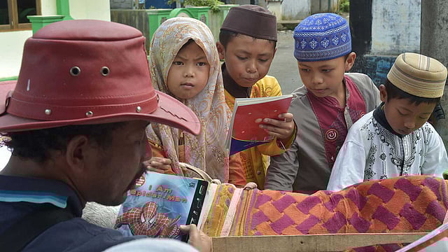 রিদওয়ান সুরুরি ঘোড়ায় করে বই নিয়ে এসেছেন। শিশুরা সেখান থেকে বই নিচ্ছে। ছবি: এএফপি