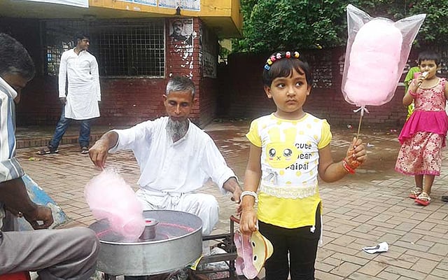 শিশু পার্কের সামনে হাওয়াই মিঠাই বানাচ্ছেন ইসমাইল হোসেন। ছবি: প্রথম আলো