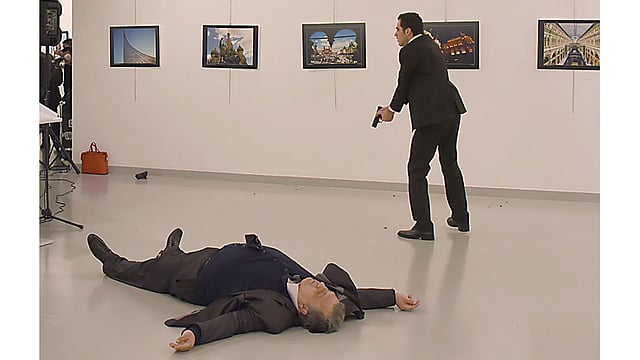 আর্ট গ্যালারির ভেতরে গুলিবিদ্ধ অবস্থায় মেঝেতে পড়ে আছেন তুরস্কে নিযুক্ত রাশিয়ার রাষ্ট্রদূত আন্দ্রেই কারলোভ। পাশেই পিস্তল হাতে হামলাকারী। ছবি: এএফপি