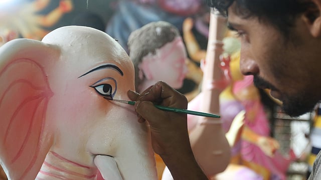 গণেশের চোখ আঁকছেন প্রতিমাশিল্পী।