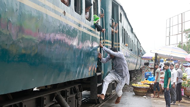 রেললাইনের ওপরেই বিভিন্ন স্থাপনা থাকায় ট্রেনকে চলতে হয় ধীর গতিতে। আশকোনার রেলক্রসিংয়ে চলমান সেই ট্রেনেই চলছে ওঠার চেষ্টা। ছবি: শুভ্র কান্তি দাশ