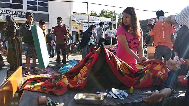 ভূমিকম্পের কারণে আহত এক নারীকে হাসপাতালের বাইরে প্রাথমিক চিকিৎসা দেওয়া হচ্ছে। লমবাক, ইন্দোনেশিয়া, ২৯ জুলাই। ছবি: রয়টার্স