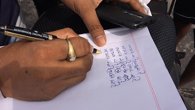 এক মোটরসাইকেল আরোহী সাদা খাতায় ১০ বার লিখতে বাধ্য হয়েছেন- ‘আমার লাইসেন্স নাই’। আসাদগেট সিগন্যাল, ঢাকা, ২ আগস্ট। ছবি: প্রথম আলো