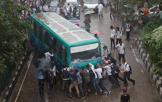 সায়েন্স ল্যাবরেটরি মোড়ে একটি বাস ঠেলে নিয়ে যাচ্ছে শিক্ষার্থীরা। এই বাসটির চালকের লাইসেন্স না থাকায় বাসটি চলতে দেয়নি তারা। ছবি: দীপু মালাকার