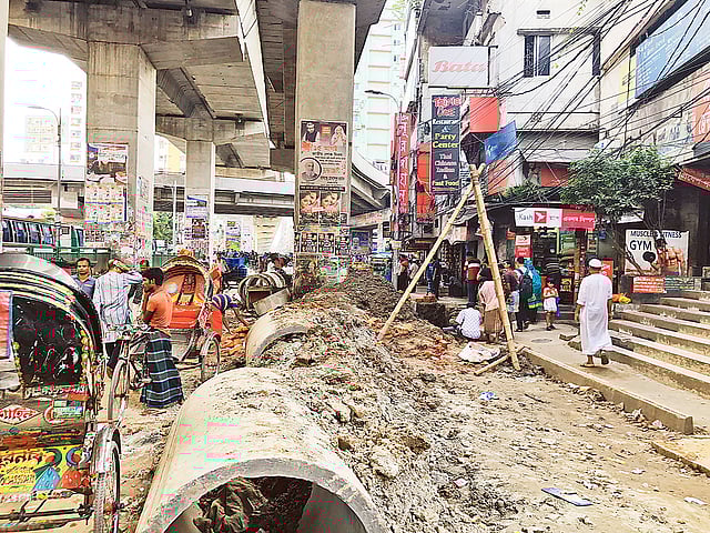 মগবাজার–মৌচাক সড়কের দুই পাশে খুঁড়ে পাইপ বসানো হচ্ছে। গতকাল দুপুরে মগবাজার মোড়ে।