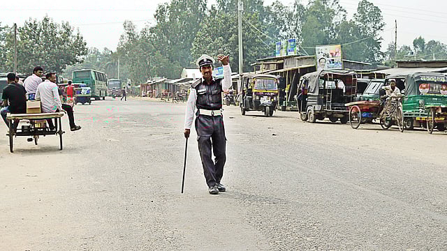 মহাদেবপুরের একটি সড়কে এভাবেই প্রতিদিন শৃঙ্খলা রক্ষার কাজ করে চলেছেন আজাহার আলী মন্ডল। ছবি: ছুটির দিনে