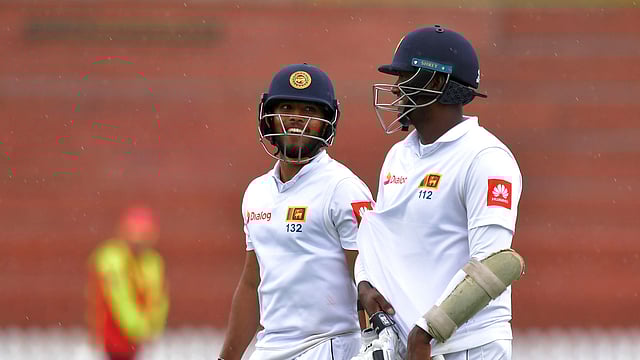 বৃষ্টি শুরু হওয়ায় মাঠ ছাড়ছেন ম্যাথুস ও মেন্ডিস। ছবি: এএফপি