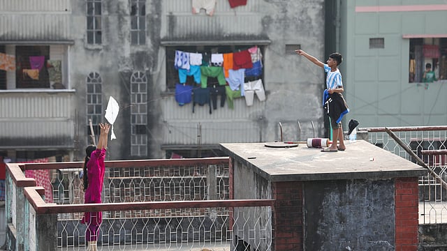 অপরের সাহায্য নিয়ে ঘুড়ি ওড়াচ্ছে এক শিশু।