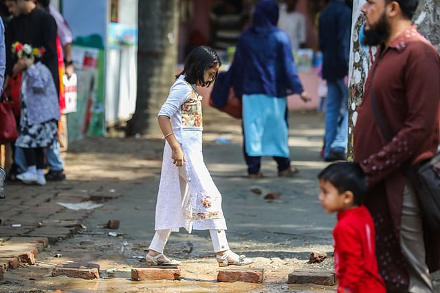 মেলা প্রাঙ্গণে জমে থাকা পানি এড়িয়ে পার হচ্ছে এক শিশু।