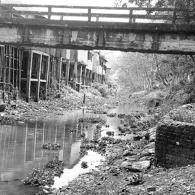 খাল দখল করে এক পাশে তৈরি করা হয়েছে স্থাপনা, ওপারে সেতু। চাঁদপুরের মতলব দক্ষিণ উপজেলার বরদিয়া আড়ং বাজার এলাকায় রাঢ়ীরখালে। ছবি: প্রথম আলো