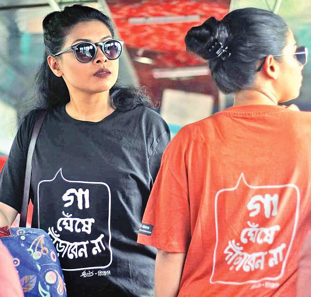 ‘গা ঘেঁষে দাঁড়াবেন না’ টি-শার্ট গায়ে দুজন নারী। ছবি: সংগৃহীত