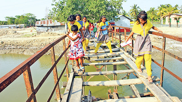 বাগেরহাটের মোংলা বন্দর পৌরসভার মাছমারা খালের ওপরের কাঠের সেতুটি অত্যন্ত জরাজীর্ণ। শিশুরা এটি পার হয় ভয়ে ভয়ে। গত সোমবার মাছমারা গ্রামে। ছবি: প্রথম আলো