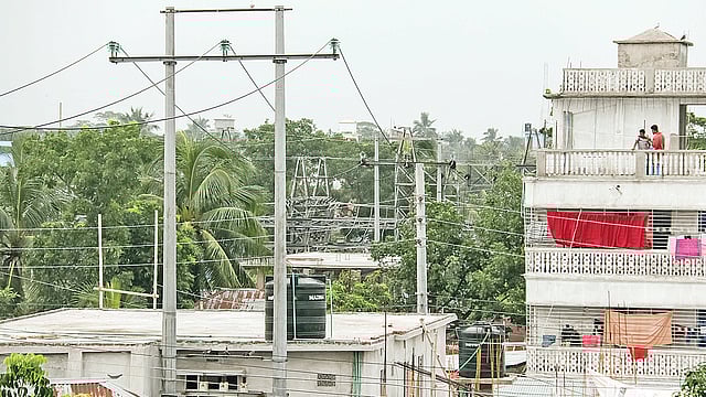 ৩৩ কেভি বৈদ্যুতিক খুঁটির নিচে ভবন নির্মাণ করে বসবাস করছে কয়েকটি পরিবার। সম্প্রতি বরিশাল নগরের পলাশপুর এলাকায়। ছবি: প্রথম আলো