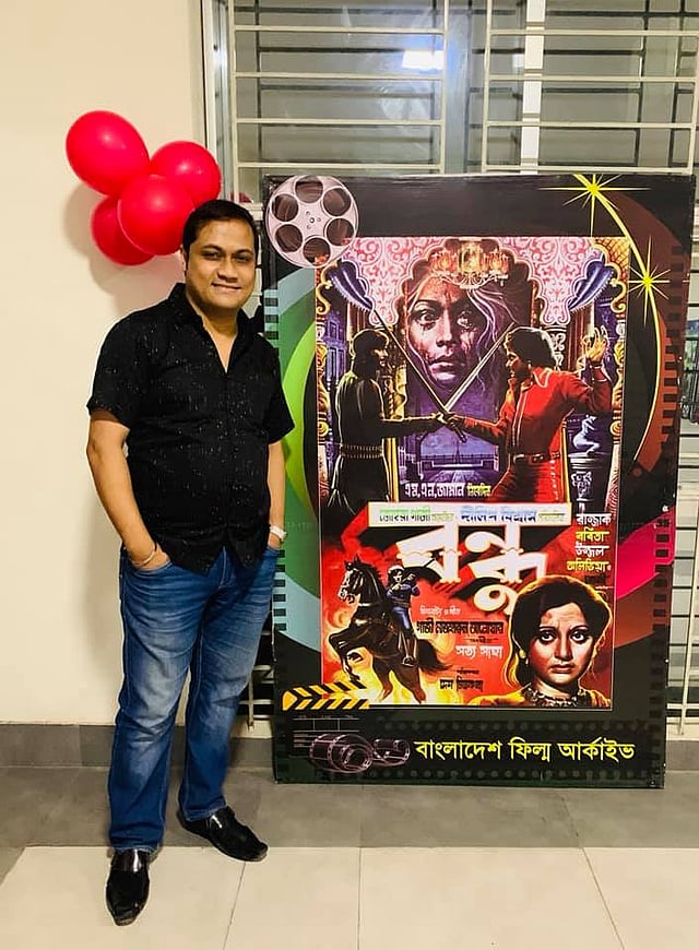 বাবার চলচ্চিত্রের পোস্টারের সামনে নির্মাতা দেবাশীষ বিশ্বাস