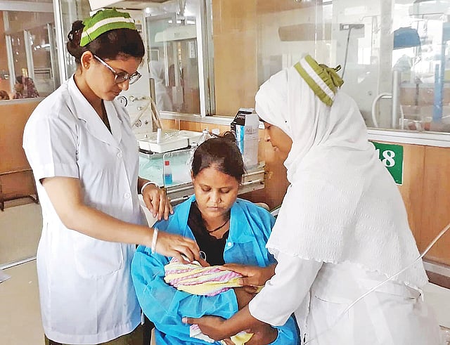 শিশুটির মা মানসিক ভারসাম্যহীন। হাসপাতালে আসা সঞ্জু দাশ নামের এক নারী শিশুটিকে বুকের দুধ খাওয়াচ্ছেন। তাঁর দুপাশে দুই নার্স শিশুটির দেখাশোনা করছেন। গতকাল চট্টগ্রাম মেডিকেল কলেজ হাসপাতালের নবজাতক ওয়ার্ডে। ছবি: গাজী ফিরোজ