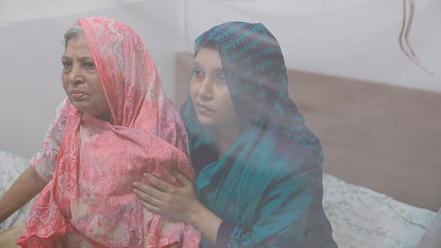 মশারির নিচে মা হোসনেয়ারার সঙ্গে মেয়ে ফারজানা হক। ছবি: সাবিনা ইয়াসমিন