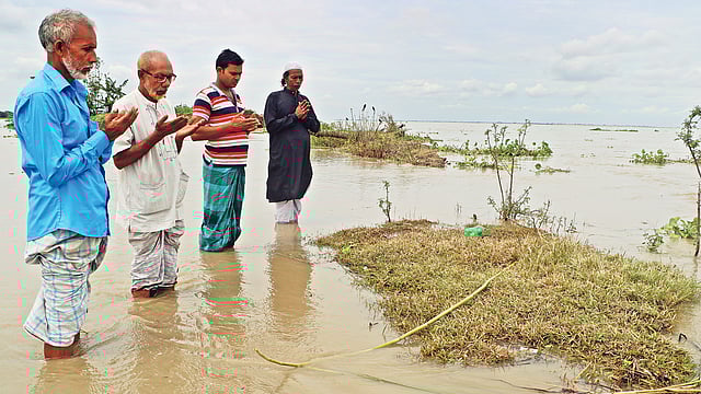 ভাঙনে অবশিষ্ট বসতভিটার পাশে থাকা মায়ের কবরটাও যেকোনো মুহূর্তে নদীতে বিলীন হয়ে যাবে। তাই জুমার নামাজের পর শেষবারের মতো তিন ভাই ও স্বজনের কবর জিয়ারত। গত শুক্রবার দুপুরে রাজবাড়ীর গোয়ালন্দের দেবগ্রামে। ছবি: এম রাশেদুল হক
