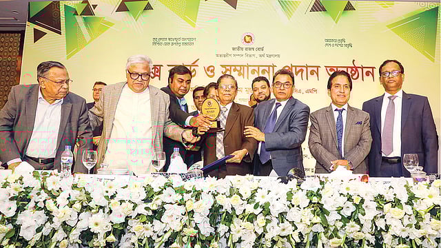 অর্থমন্ত্রী আ হ ম মুস্তফা কামালসহ অন্যদের কাছ থেকে সেরা করদাতার সম্মাননা নিচ্ছেন কাউছ মিয়া। গত বৃহস্পতিবার রাজধানীর র্যাডিসন হোটেলে। ছবি: প্রথম আলো