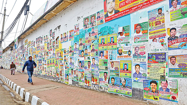পোস্টারে ঢেকে গেছে দেয়ালচিত্র। গতকাল মেয়র আনিসুল হক সড়কে। ছবি: প্রথম আলো