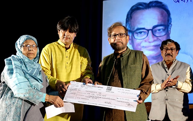 পুরস্কারের সম্মানী হিসেবে আসাদুজ্জামান নূরের হাতে এক লাখ টাকার চেক প্রদান করেন মমতাজউদদীন আহমদের স্ত্রী। ছবি: প্রথম আলো