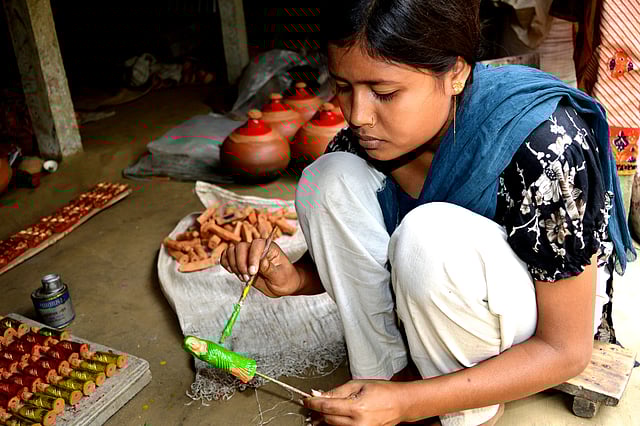 পালবাড়িতে এভাবেই এক কিশোরীকে পড়াশোনার পাশাপাশি তৈরির পর পুতুলে রং করতে দেখা গেছে। ছবি: লেখক