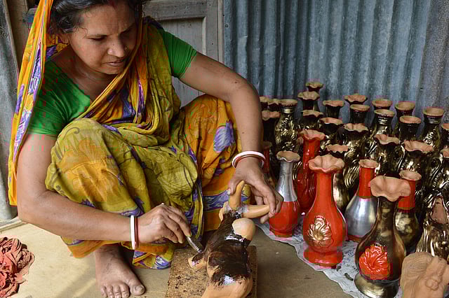 উপজেলার বড়িলপাড়ায় মৃৎশিল্পী লক্ষ্মী রানী মাটির খেলনায় রং করছেন। ছবি: লেখক