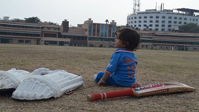 মাঠে বসে আছে টেন্ডুলকারের ১০ মাস বয়সী ভক্ত। ছবি: শচীন টেন্ডুলকারের টুইটার পেজ