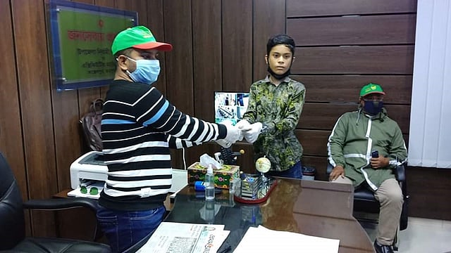 জয়পুরহাটের আক্কেলপুরে সপ্তম শ্রেণির ছাত্র মওদুদ হাসান টিফিনের জমানো টাকা ইউএনও জাকিউল ইসলামের কাছে হস্তান্তর করছে। ছবি: সংগৃহীত