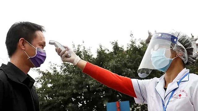 ভিয়েতনামের রাজধানী হ্যানয়ের রাজপথে এক ব্যক্তির তাপমাত্রা পরীক্ষা করছেন স্বাস্থ্যকর্মী। ছবি: রয়টার্স