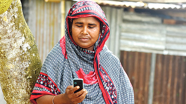 মোবাইলে বন্ধুসভার অর্থসহায়তা পাওয়া এক নারী। গত রোববার পাবনা সদর উপজেলার মালিগাছার ভজেন্দ্রপুর গ্রামে। ছবি: প্রথম আলো
