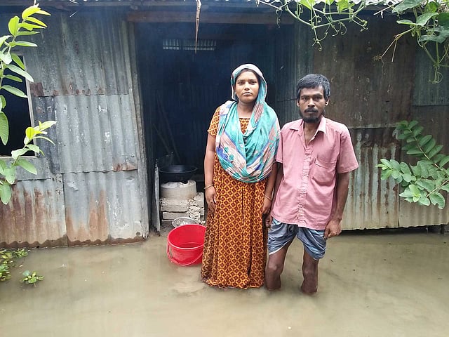 বাড়ির উঠানে পানিতে দাঁড়িয়ে আছেন দিনমজুর রোকন মিয়া ও তাঁর স্ত্রী শিল্পী আক্তার। আজ রোববার বিকেলে টাঙ্গাইলের মির্জাপুর উপজেলার মহেড়া ইউনিয়নের কড়াইল গ্রামে। ছবি: প্রথম আলো