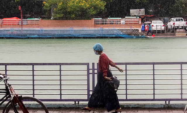 স্বাস্থ্যবিধি মেনে বৃষ্টিতে ভিজেই ফুটপাত দিয়ে হেঁটে যাচ্ছেন তিনি। বিবির পুকুর পাড়, বরিশাল নগর, ১৯ জুলাই। ছবি: সাইয়ান।