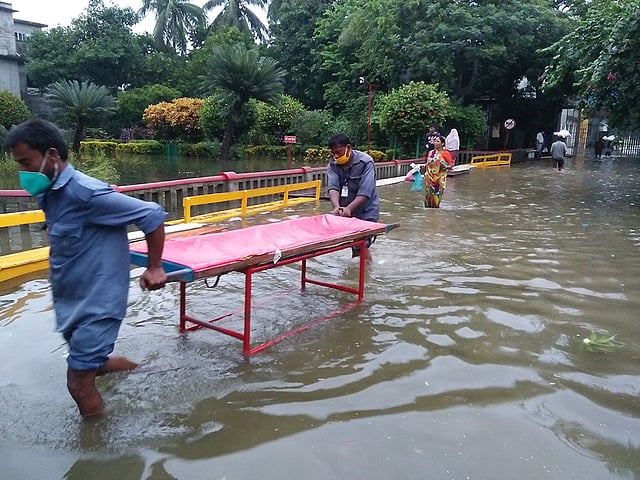 বন্যার পানির মধ্যেই রোগী বহন করতে স্ট্রেচার নিয়ে যাচ্ছেন স্বাস্থ্যকর্মীরা। ছবি: প্রথম আলো