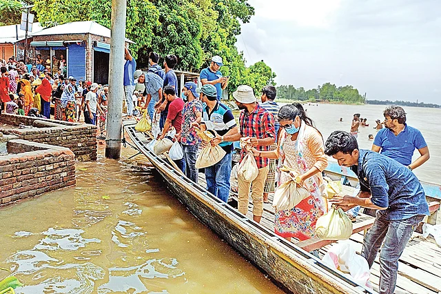 পাবনার বেড়া উপজেলার বন্যাকবলিত মানুষের মধ্যে প্রথম আলো ট্রাস্টের উদ্যোগে ত্রাণসহায়তা পৌঁছে দিচ্ছেন পাবনা ও বেড়া বন্ধুসভার সদস্যরা। গতকাল সকালে উপজেলার হাটুরিয়া-নাকালিয়া ইউনিয়নের প্যাঁচাকোলা গ্রামে। ছবি: হাসান মাহমুদ
