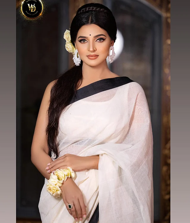 কালো পাড়ের সাদা শাড়ির সঙ্গে স্লিভলেস সাদা ব্লাউজে ষাটের দশকের রেট্রো আমেজ রেখেছেন বর্ষা। হালকা পাফ করে মাঝে সিঁথি রেখে ছেড়ে দেওয়া চুলেও সাবেকি স্টাইল।