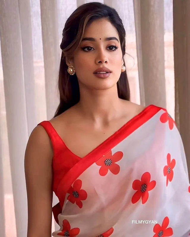 উজ্জ্বল কমলা বর্ডার আর ফুলেল প্রিন্টের সাদা শিফনের সঙ্গে জাহ্নবী পরেছেন কমলা স্লিভলেস ব্লাউজ