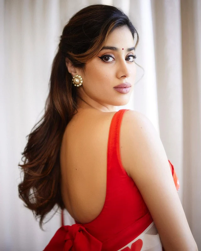 ব্যাংস রেখে রেট্রো স্টাইলে চুল বেঁধেছেন জাহ্নবী। কানে মুক্তার বড় স্টাড। ছোট লাল টিপ , টেনে দেওয়া আইলাইনার, কাজল আর ন্যুড ম্যাট লিপস্টিক দিয়েছেন তিনি।