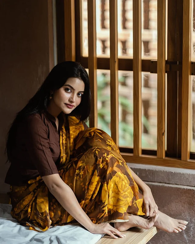 হলুদ আর কফি রঙের মিশেলে অভিনেত্রী নাজিফা তুষি যেন হয়ে উঠেছেন আরও বেশি মোহময়ী। কফি বা ডার্ক ব্রাউন ব্লাউজের সঙ্গে তাঁর ফ্লোরাল শাড়ি বেশ ফুটেছে।