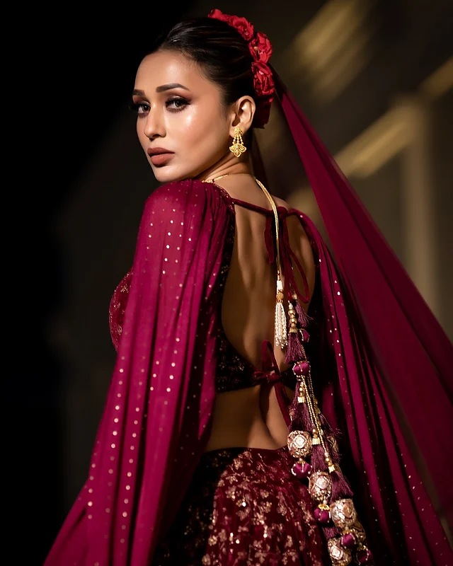 ব্যাকলেস ডিজাইনটি নজরকাড়া। এতে আছে জমকালো ট্যাসেলের ব্যবহার। সোনার গয়না পরেছেন মিমি সঙ্গে। আর চুলে লালা গোলাপের সারির সঙ্গে আছে মেরুন ওড়না
