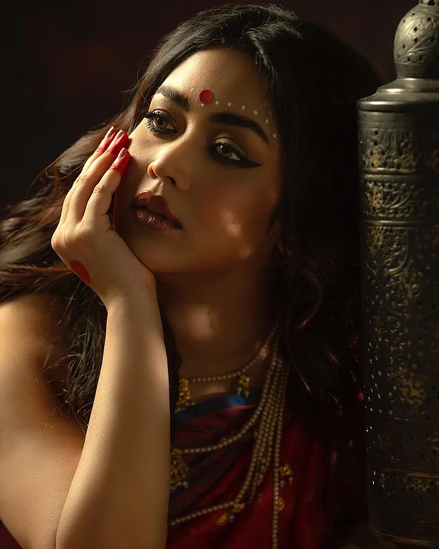 নাটকীয় টানা আইলাইনার, পুরু লাল ঠোঁট, লাল টিপের সঙ্গে কপালে চন্দনের সাদা ফোঁটা, হাতের মেহেদি আর ব্লাউজ বিনে আটপৌরে শাড়ির সঙ্গে গহনা। বিষাদমাখা নববধূর রূপে মুগ্ধ করছেন ভাবনা।