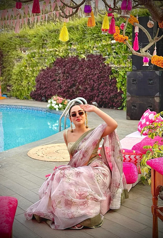 এ সময়ের দাওয়াত কিংবা পার্টির লুকে তমা মির্জার মতো এমন এথনিক লুক বেছে নেওয়া যেতে পারে। স্লিভলেস ব্লাউজের সঙ্গে নায়িকা ফ্লোরাল প্রিন্টের অরগাঞ্জা শাড়ি পরেছেন। কানে বড় আকারের ঝোলানো দুল, স্লিক বান হেয়ারস্টাইল আর সামার সানগ্লাসে ফ্রেমবন্দী হয়েছেন তিনি।