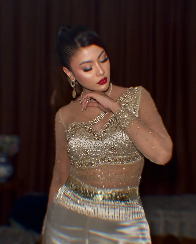 গ্ল্যাম ফিনিশের মেকওভারে পুরোপুরি ডিভা লাগছেন তিনি। সাহসী লাল লিপস্টিক, স্মোকি আই মেকআপ আর হাইলাইটেড চিকবোন আকর্ষণ কাড়ছে