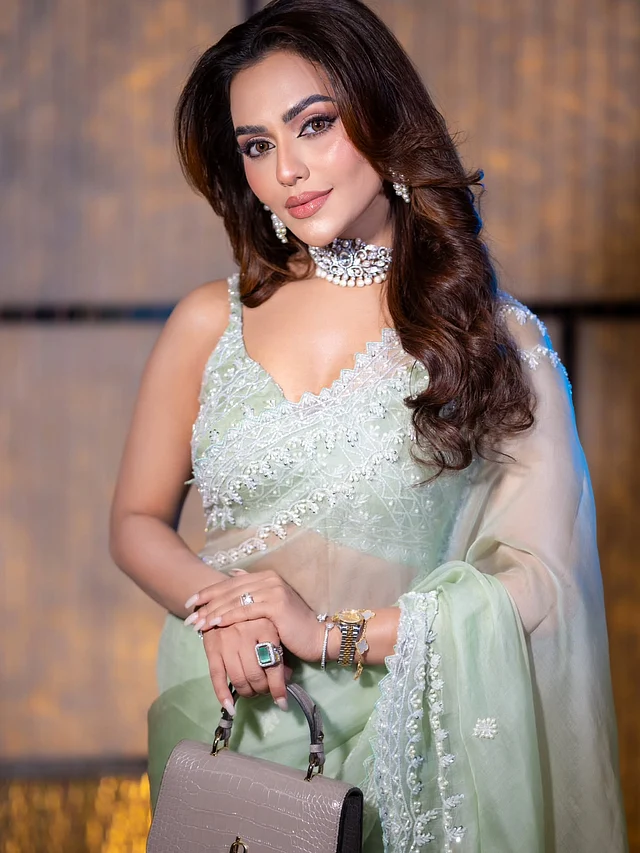 জুটি হয়েছে একই রঙের ডিপনেক লাইনের স্লিভলেস ব্লাউজ। সঙ্গে নিয়েছেন মিনি হ্যান্ড ব্যাগ।