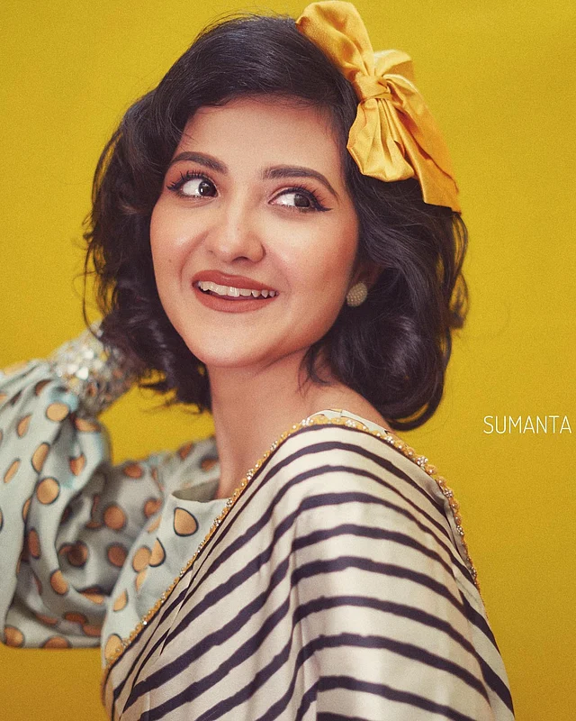 রেট্রো লুকে ফ্রেমবন্দী হয়েছেন মিষ্টি এই অভিনেত্রী। বল প্রিন্টের ব্লাউজের সঙ্গে স্ট্রাইপের শাড়ি পরেছেন। চোখে টানা করে দেওয়া কাজল আর ছোট চুলে শোভা পাচ্ছে হলুদ বো ক্লিপ।