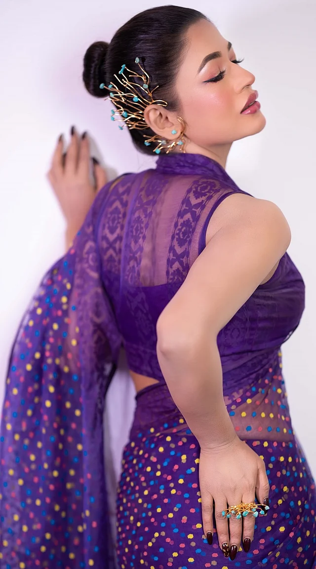 সামনেড্রেপ হল্টার স্টাইলের সঙ্গে দারুণ ফিটিংয়ের এই হাইনেক ব্লাউজে শিয়ার এফেক্ট বাড়াচ্ছে আবেদন।