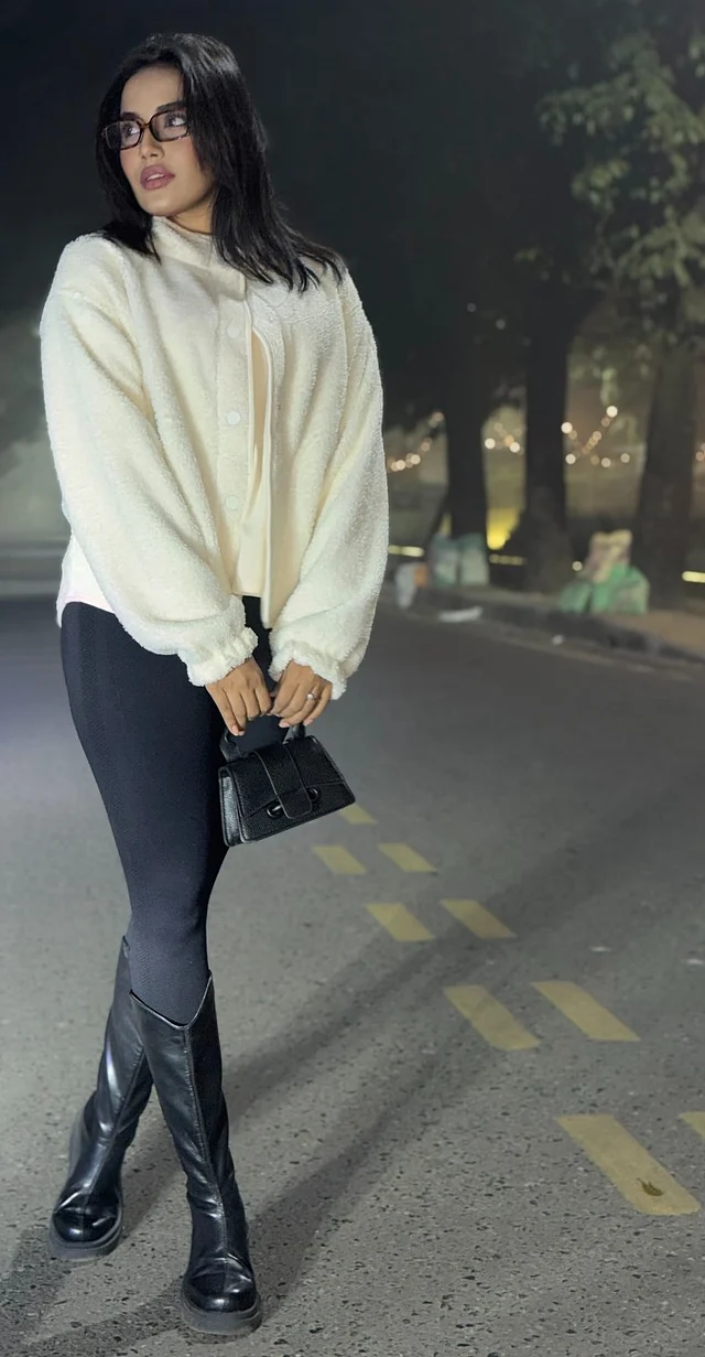 সামিরা মাহিকে দেখা যাচ্ছে অফ হোয়াইট সোয়েটার, ফিটেড জিন্স, হাই বুটস আর মিনি ব্যাগে